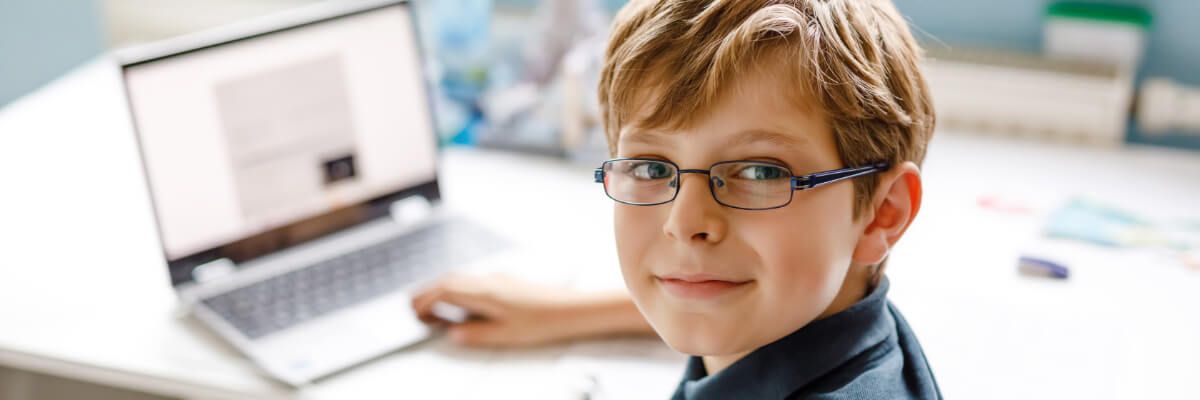 Chłopiec w okularach siedzący przed komputerem
