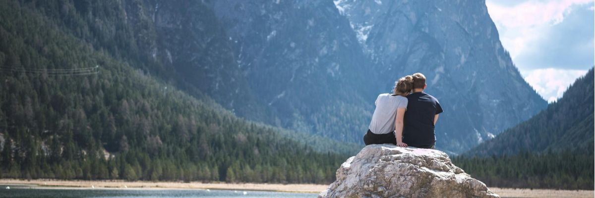 para siedząca na skale nad jeziorem w górach