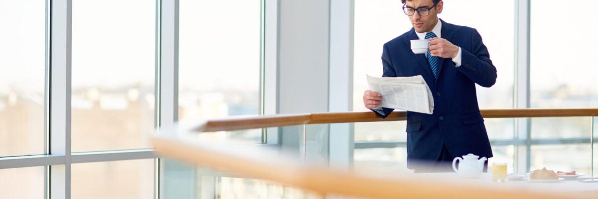 mężczyzna z gazetą i filiżanką w ręku